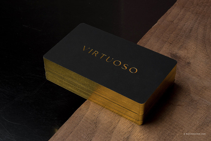 Luxury black suede business cards with gold foil logo and gold edge finish, featuring "Virtuoso" branding by RockDesign.