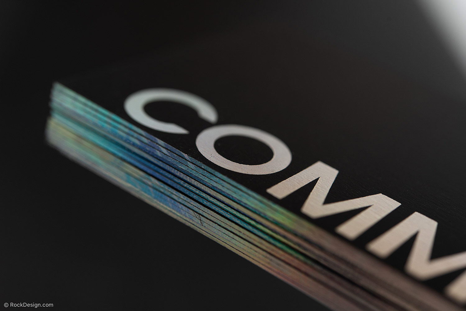 Close-up of a black luxury business card with silver lettering and colorful metallic card edges, showcasing premium edge finishing and high-end business card printing.